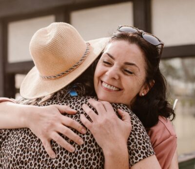 Two women embrace warmly, all smiles, a picture of the wisdom and comfort friends can bring