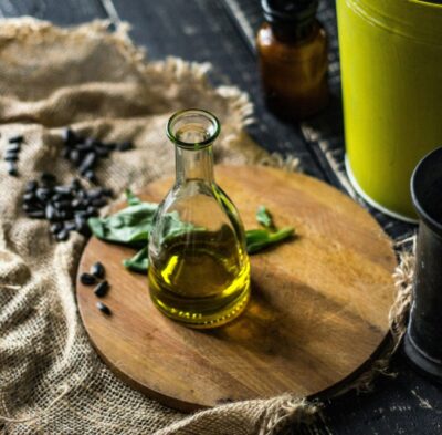 A small glass bottle of golden olive oil on a wooden board, like the widow's one jar left