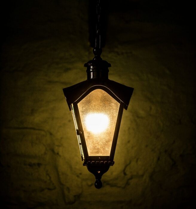 A single lantern glows warmly against darkness, a picture of faith shining where it's needed