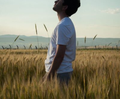 A man in a wheat field looks up toward a clouded sky, a picture of hearing God's promise