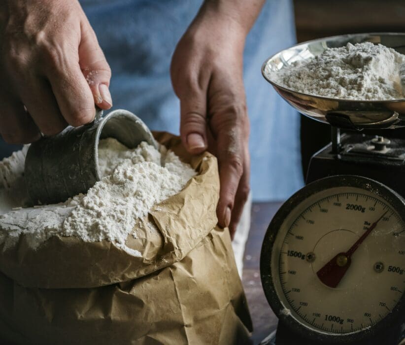 Flour is poured onto an old kitchen scale, echoing the flour sold cheap at Samaria's gate