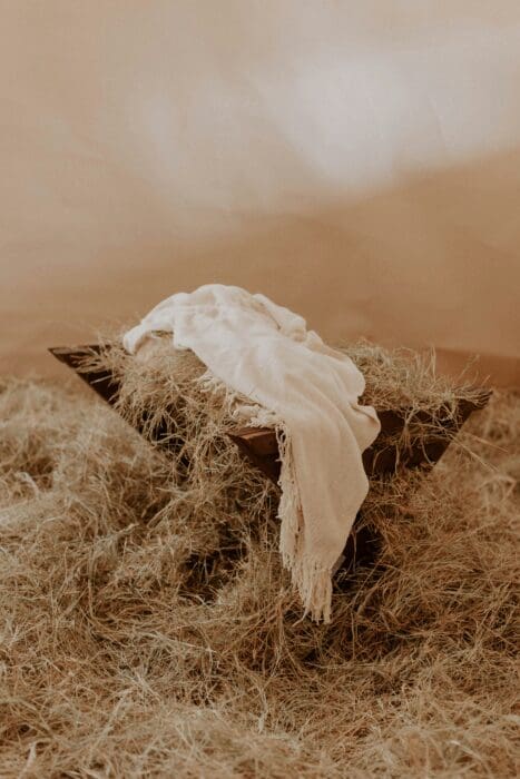 A manger bed of hay draped with plain white cloth, a picture of the good news God sent in His Son