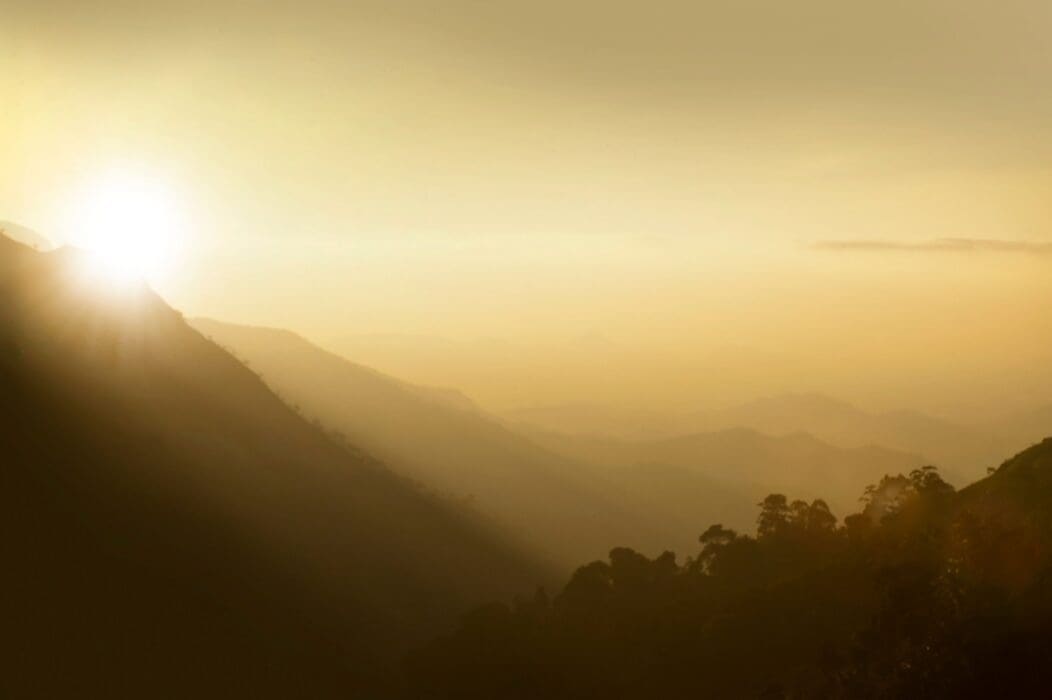 Sunlight breaks through misty mountain ridges at dawn, a picture of good news breaking into view