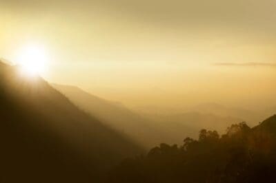 Sunlight breaks through misty mountain ridges at dawn, a picture of good news breaking into view