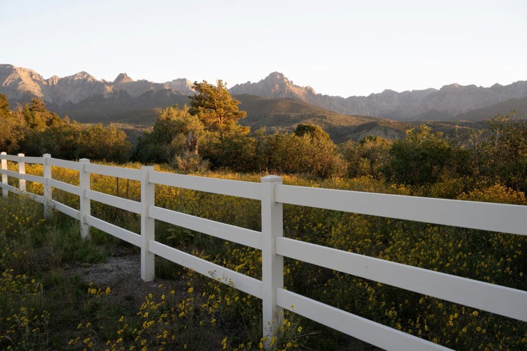A white ranch fence lining a wildflower meadow at golden hour, a picture of the boundaries God sets on sin.
