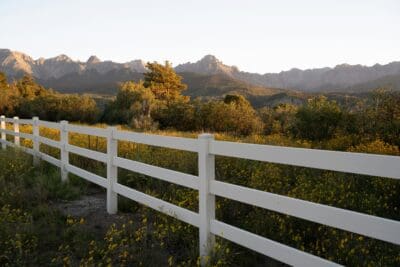 A white ranch fence lining a wildflower meadow at golden hour, a picture of the boundaries God sets on sin.