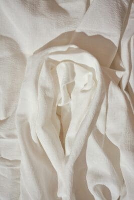 Soft folds of rumpled white linen cloth in sunlight, recalling the grave linens Lazarus left behind.