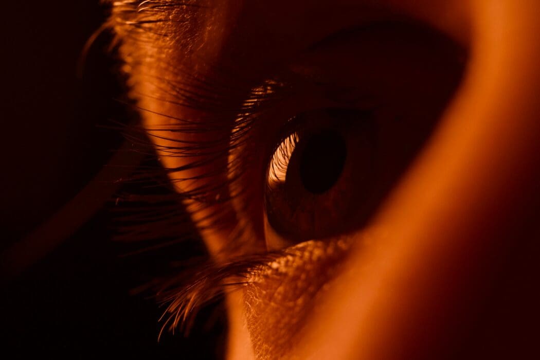 An extreme close-up of a human eye lit in warm amber light, asking where your eyes are really focused.