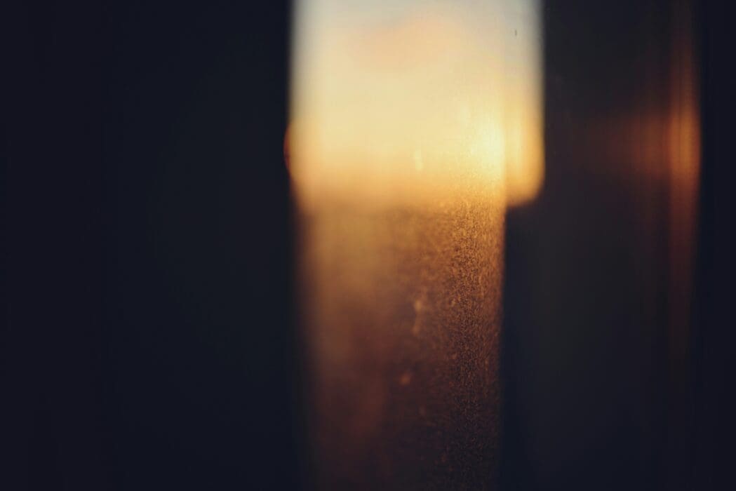 Warm golden light breaking through a blurred window, picturing the law's light exposing hidden sin.