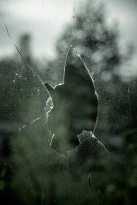A jagged hole shattered through a dusty windowpane, a fitting image of evil breaking into the world.