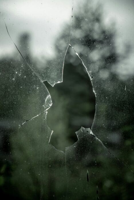 A jagged hole shattered through a dusty windowpane, a fitting image of evil breaking into the world.